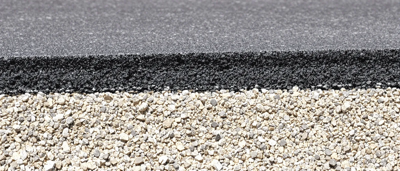 Saw cut road edge showing stacked asphalt layers over a limerock base
