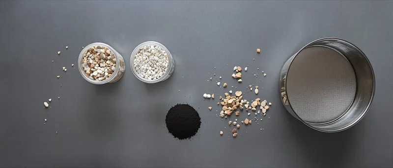 Overhead view of testing sieves and trays of graded aggregate on a lab bench