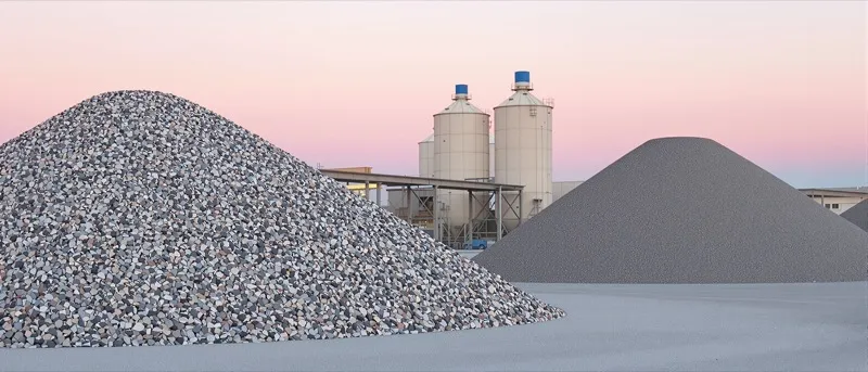 Front end loader scooping aggregate from a stockpile at an asphalt plant at sunrise