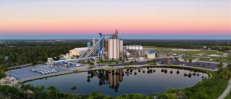 Aerial view of an asphalt plant with silos and aggregate stockpiles at sunrise in Florida