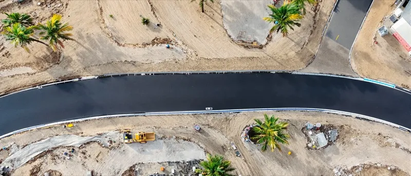 Aerial view of a new asphalt road curving through a Florida subdivision under construction