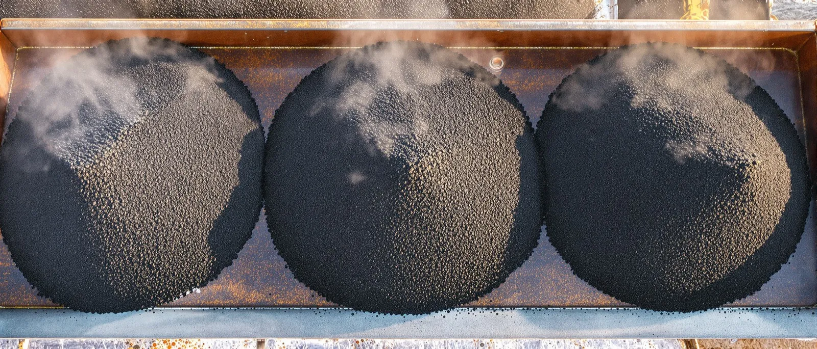 Three piles of asphalt mix with fine, medium and coarse stone side by side